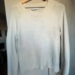 Vit stickad tröja från ONLY - Mysig vit stickad tröja från ONLY i storlek XS. Tröjan har en bred ribbad rund halsringning och långa ärmar. Perfekt för kyliga dagar och enkel att matcha med jeans eller kjol. Materialet är mjukt och ger en skön känsla.