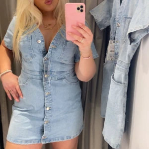 Ljusblå jeansklänning Zara - Säljer en ljusblå jeansklänning med kort ärm och knappstängning framtill. Klänningen har två bröstfickor och markerad midja för en snygg siluett. Från Zara, i storlek XL men passar L/M