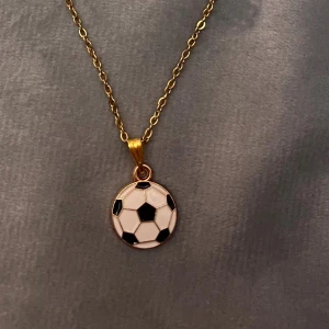 Fotboll halsband guld imitation - Ett fint halsband med en liten fotboll. Trädd på kedja i guldimitation, justerbar 40-45 cm. Fotbollen är ca 1,2 cm i diameter.   Perfekt present för den som älskar fotboll!⚽️ 