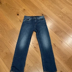 Blå jeans från Replay, rak modell - Säljer ett par klassiska blå jeans från Replay med raka ben och femficksdesign. Jeansen har snygga slitningar framtill och är tillverkade i ett mjukt bomullsmaterial. Perfekta för dig som gillar en tidlös och avslappnad look.