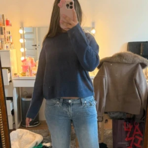 Mörkblå stickad tröja - Mysig mörkblå stickad tröja med rund hals och lång ärm. Tröjan har en loose passform och är perfekt för kyligare dagar. Enkel och stilren design som passar till jeans eller kjol.