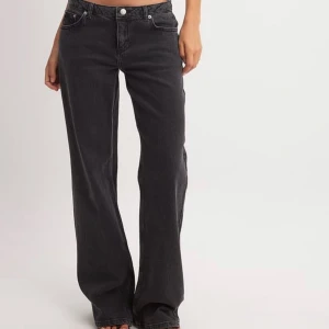 Svarta low waist jeans från NA-KD - Snygga svarta jeans från NA-KD med wide passform och klassisk femficksdesign. Jeansen har låg midja och raka ben med lite utsvängd siluett. Tillverkade i slitstarkt denim-material som ger en cool och avslappnad vibe.