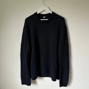 Mörkblå stickad tröja från ARKET - Mörkblå stickad tröja från ARKET i storlek L. Klassisk rund hals och långärmad modell med ribbade muddar vid ärmslut och nederkant. Perfekt för dig som gillar enkel och stilren design med en chill vibe. 4D9