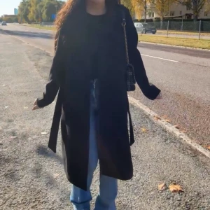 Svart lång kappa med bälte - Säljer en svart lång kappa från vero moda med bälte i midjan och klassisk krage. Jackan har en stilren och rak passform med långa armar. Passar dig som vill ha en snygg och enkel look under höst och vinter.