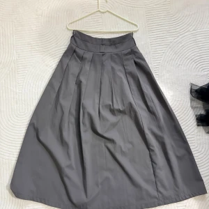 Grå långkjol med veckad design - Snygg grå långkjol med klassisk A-linjeform och bred linning. Kjolen har flera markerade veck som ger ett stilrent och elegant fall. Perfekt för dig som gillar minimalistisk och tidlös stil.