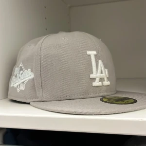 Grå LA Dodgers keps New Era 59FIFTY - Snygg grå LA Dodgers keps från New Era 59FIFTY Cooperstown Collection. Kepsen har broderad LA-logga framtill, MLB-logga bak och New Era-logga på sidan. Rak skärm och klassisk passform. Perfekt för dig som gillar streetstyle och sport.