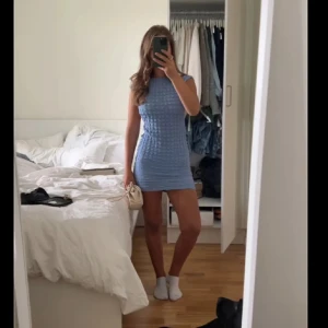 Ljusblå kort klänning med öppen rygg - Supersöt ljusblå kortklänning med strukturerat mönster och öppen rygg. Klänningen är ärmlös och har en tight passform som framhäver figuren. Perfekt för varma dagar och somriga tillfällen.