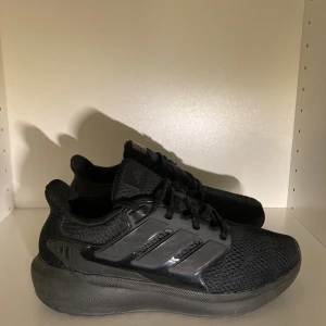 Adidas Cloudfoam skor  - Säljer ett par helsvarta Adidas sneakers med klassiska tre ränder på sidan. Skorna har ovandel i mesh för bra andningsförmåga och en chunky Cloudfoam-sula för extra komfort. Perfekta för dig som gillar stilrena och sportiga skor med snörning.