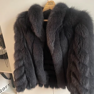 Mörkblå äkta pälsjacka - Säljer en fluffig och lyxig mörkblå pälsjacka med bred krage och voluminösa ärmar. Jackan har en loose passform och är av äkta päls. Skulle säga s/m