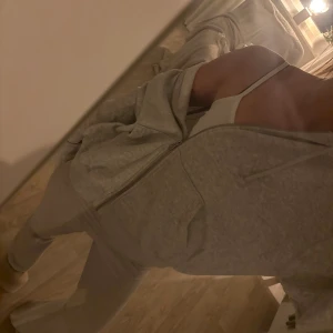 Grå hoodie med dragkedja från Weekday - Mysig ljusgrå hoodie från Weekday med dragkedja framtill, huva med snörning och två stora fickor. Perfekt för chill dagar eller när du vill ha en enkel och clean look. Tillverkad i mjuk bomullsblandning för extra komfort. Känns större i storleken än S mer M skulle jag säga.