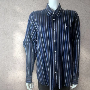  skjorta från Tommy Hilfiger - Snygg skjorta från Tommy Hilfiger med vertikala ränder i olika blå nyanser och vitt. Klassisk krage, långärmad och med vita knappar framtill. Liten logotyp på bröstet. Perfekt för dig som gillar stilrena och coola plagg. #skjorta #tommyhilfinger