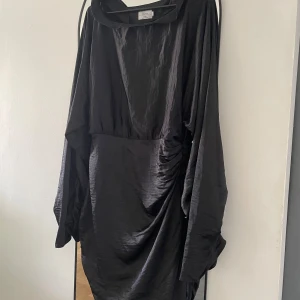 Långärmad svart klänning - Väldigt fin långärmad klänning från Hanna Schönbergs collection med NA-KD, storlek 40 i väldigt fint skick. Dragkedja längs ena sidan, vida ärmar & fina detaljer på ärmarna och sidorna. Säljer även en likadan i grön. 💕