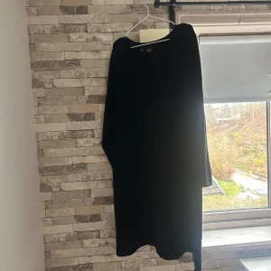 Svart långärmad klänning från bpc - Svart långklänning från bpc bonprix collection i storlek 2XL. Klänningen har lång ärm och en enkel, rak siluett med rund halsringning. Materialet är mjukt och känns som bomull, perfekt för dig som gillar stilrena och bekväma plagg.