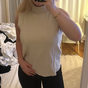 Beige polotopp i manchester - Säljer en beige polotopp i mjuk manchester med ribbad hög krage. Toppen är ärmlös och har en clean, rak passform