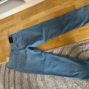 Lee Brooklyn ljusblå jeans W34 L32 - Säljer ett par klassiska Lee Brooklyn jeans i ljusblå denim. Modellen har raka ben, normal passform och snygga kontrastsömmar. Jeansen har fem fickor och Lee-logga på bakfickan. Perfekta för en avslappnad och stilren look.