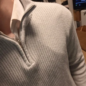 Ljusgrå stickad half zip-tröja 157 - Säljer en ljusgrå stickad tröja från 157 i storlek L. Tröjan har en ribbad struktur, hög krage och half zip-dragkedja framtill. Långärmad och perfekt för kyliga dagar, snygg att ha över en skjorta. Enkel och stilren design som funkar till jeans.