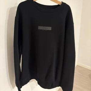 Svart sweatshirt från Jack & Jones - Svart sweatshirt från Jack & Jones med diskret logga på bröstet. Tröjan har rund hals, långa ärmar och ribbade muddar vid ärmslut och nederkant. Mjuk insida i bomullsmix som gör den skön att bära. Perfekt för chill dagar och enkel att matcha.