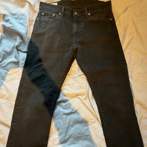 Svarta Levi's Premium jeans straight fit - Svarta jeans från Levi's Premium med klassisk femficksdesign och raka ben. Jeansen har en stilren look med svarta sömmar och metallknappar. Passar dig som gillar enkel och tidlös stil. Materialet är slitstarkt jeans och midjan är normal.