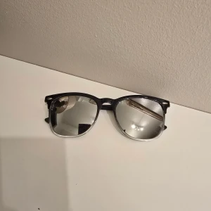 Svarta solglasögon med spegelglas - Snygga solglasögon med svart båge och spegelblanka glas. Klassisk form som passar till de flesta outfits och ger en cool vibe. Perfekta för soliga dagar när du vill sticka ut lite extra.