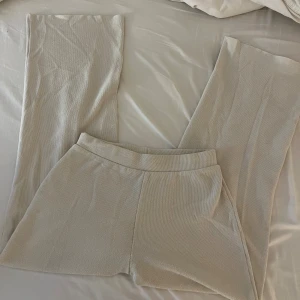 Beiga stickade byxor från Zara - Snygga beiga stickade byxor från Zara i storlek S. Byxorna har en rak och lite vidare passform med elastisk midja för extra komfort. Perfekta att styla med en matchande topp för en clean och trendig look.
