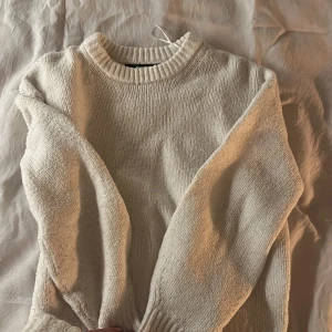 Vit stickad tröja med rund hals - Mysig vit stickad tröja med rund halsringning och breda muddar vid ärmslut och nederkant. Tröjan har en relaxed fit och är perfekt för lager-på-lager. Enkel och stilren design som passar till allt. Har även en likadan i svart💗