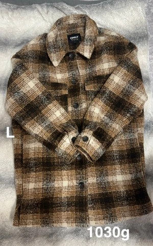 Rutig jacka från ONLY i bruna toner - Snygg rutig jacka från ONLY i bruna, beige och vita nyanser. Jackan har klassisk krage, knäppning framtill med svarta knappar och två bröstfickor. Perfekt lager-på-lager-plagg med lång ärm och avslappnad passform.🌸Fint använt skick. Storlek L