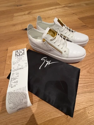 Giuseppe Zanotti skor - Säljer dessa riktigt schyssta Giuseppe Zanotti sneakers i vit och guld. Köpa på nk, använda max 2-3 gånger men även riktigt skonsamt. De är även rengjorda så man får en känsla av nya Skor. Faller mig tyvärr inte i smaken och därav säljs de.