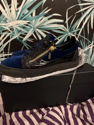Blå och svarta sneakers med dragkedja - Säljer nu dessa extremt snygga Giuseppe Zanotti skor där nypris är 4500kr. Säljer skorna pågrund av ingen användning av det. Finns en defekt och det är vid snöret där en av där man dragbil snöret har släppt lite, annars är det typ som i nyskick. Säljer de för 2399, vid snabb affär kan jag gå ner