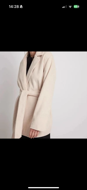 Beige omlott kappa med bälte - Snygg beige kappa med omlott-design och bälte i midjan. Jackan har breda slag, lång ärm och en loose passform som ger en chill och modern vibe. Perfekt för dig som gillar stilrena och enkla plagg med lite extra edge. Extremt sparsamt använd. Nypris 900kr.