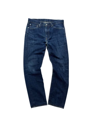 Levi's 513  - Klassiska blå Levi's 513 jeans med rak passform och femficksmodell. Jeansen har en mörk tvätt, kontrastsömmar och Levi's ikoniska läderpatch bak i midjan. Jeansen har en lagning: se bild 4.          Hör av dig vid frågor eller funderingar!