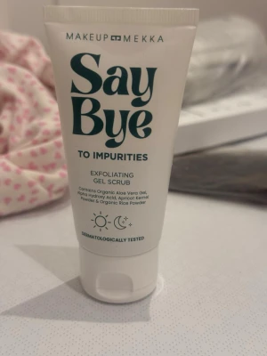 Makeup Mekka – Say Bye to Impurities Exfoliating Gel Scrub (50 ml) - Denna Say Bye to Impurities Exfoliating Gel Scrub från Makeup Mekka är en skonsam men effektiv ansiktsskrubb som kombinerar naturliga exfolierande partiklar från ris och aprikoskärnor för att varsamt avlägsna döda hudceller och ge huden en klarare, jämnare lyster. Formulan är berikad med ekologisk aloe vera-gel, fruktextrakt och AHA-syror (glykolsyra, mjölksyra och mandelsyra) som hjälper till att förbättra hudstrukturen, medan den fräscha gelkonsistensen gör den lätt att massera utan irritation