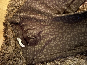 Bruna leopardmönstrade byxor från Monki - Snygga svarta byxor från Name It med leopardmönster. Byxorna har en utsvängd passform och är gjorda i ett mjukt och lätt material som känns skönt mot huden men ändå en kvalitébyxa. Perfekta för lek, bus och fashion med ett coolt mönster.