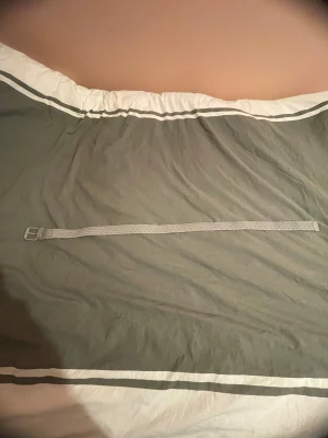 Grå Urban Classics bälte - Snyggt grått västbälte från Urban Classics med metallspänne och flätad design. Bältet är gjort i syntetmaterial och har en stilren look som passar till västar. Perfekt för att ge din outfit en extra touch.