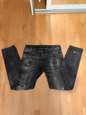 Grå Jeans från Jack & Jones - Säljer ett par gråa skinny jeans från Jack & Jones i storlek W32 L32. Jeansen har slitna detaljer, knappt använda (typ 2-3 gångerk), modell Glenn.