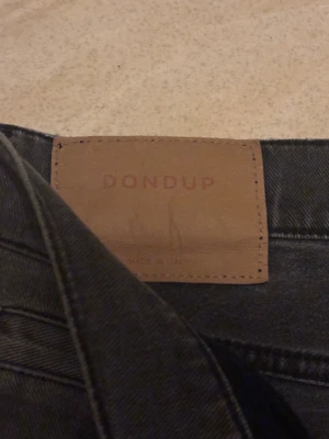 Grå jeans från Dondup George  - Snygga grå jeans från Dondup, tillverkade i Italien. Modellen har fem fickor, smal passform och klassisk knappstängning. Jeansen har en mörkgrå tvätt och är gjorda i stretchigt jeanstyg som sitter tajt längs benen.