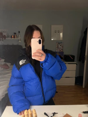 Blå pufferjacka från The North Face - Säljer en blå och svart pufferjacka från The North Face💕 Jackan har hög krage, dragkedja framtill och snörning i nederkant. Den har ny dragkedja