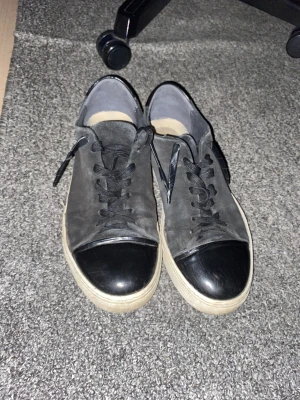 Svarta sneakers från sneaky Steve shoes  - Svarta sneakers med mocka liknande ovandel och blanka detaljer på tå och häl. Skorna har vita, platta sulor och klassisk snörning . Snygg kontrast mellan material och en stilren look som passar till det mesta 