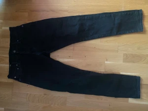 Svarta Levis 501 jeans W30 L30 - Svarta Levis 501 jeans med klassisk femficksdesign och raka ben. Jeansen har knappgylf och är tillverkade i slitstarkt bomullsmaterial. Passar dig som gillar en tidlös och clean look. Perfekt för dig som vill ha ett par jeans med ikonisk stil. Säljer även några andra jeans och mjukisbyxor. Kom med pris