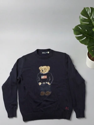 Mörkblå Ralph lauren teddy björn tröja M - 🧸 Ralph Lauren Teddy Bear Knit – Mörkblå 💙 Färg: Mörkblå, klassisk och stilren 📏 Storlek: M, sitter som en M ✨ Skick: Mycket bra, knappt använd 🐻 Söt nallebjörn i mitten som sticker ut 🧵 Mjukt och bekvämt material, perfekt för kalla dagar 🌟 Stilren och ikonisk design från Ralph Lauren 🛍️ Passar perfekt både till vardag och fest 🎁 Perfekt som present till dig själv eller någon annan 📸 Se bilder för detaljer och mönste