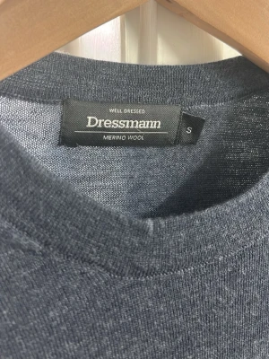 Mörkgrå merinoulltröja Dressmann S - Snygg mörkgrå tröja från Dressmann i mjuk merinoull. Klassisk rund hals och långärmad modell som passar perfekt till lager-på-lager. Stilren och enkel design utan mönster eller detaljer, vilket gör den lätt att matcha med andra plagg.