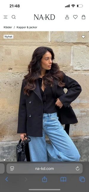 Svart kavajrock med bälte från NA-KD - Stilren svart jacka från NA-KD med band och vadderade axlar. Jättesnygg men tyvärr lite för stor för mig. Storlek 34/S med uprsprungspris 1299. Har inte använt den så den kommer med prislappen på!🥰