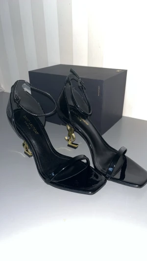 Saint Laurent svarta sandaler med YSL-klack - Säljer ett par svarta sandaler från Saint Laurent med ikonisk YSL-logga i guld som klack .           Helt oanvända 😁                                                  De är perfekta presenten  till jul🎄💕