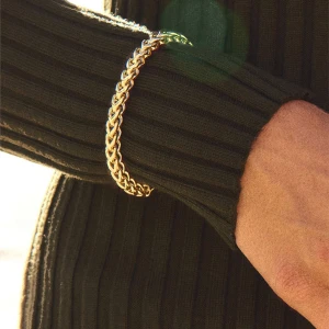 Flätat guldarmband chunky stil - Snyggt armband i chunky design med flätad kedja i guldton. Perfekt statement piece som lyfter vilken outfit som helst. Låset är diskret och smidigt, och armbandet har en riktigt lyxig känsla.