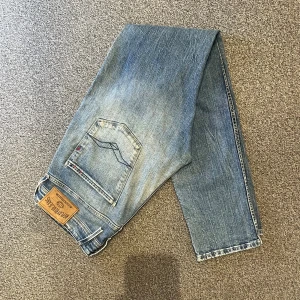 Replay Anbass jeans i storlek W33/L34 - Replay Anbass jeans i storlek W33/L34. Mörkblå denim med slim fit-passform och stretch som gör dem bekväma. Bra skick utan hål eller fläckar. Nypris runt 1500–2000 kr.  Mått: A (midja): 44 cm B (lårvidd): 29cm C (fotvidd): 18 cm D (innerbenslängd): 83 cm  Säljes för 499 kr. 