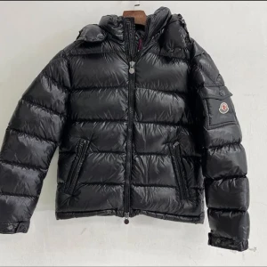 Moncler Maya - Helt ny och oanvänd Moncler Maya jacka. 10/10 skick. Väldigt fin och bekväm jacka. Det är storlek 3, vilket motsvarar M/L, skulle nog säga att de passar både M och L. Bilderna är tagna i olika ljus, från bild 2 och 5 är det väldigt mycket ljus, därför glänser den mycke, men den är inte så glansig. Den har en fungerande Nfc tag som ni ser på bild 5. Köp dig en billig vinter jacka så du är redo för vintern. Rekommenderar starkt! 