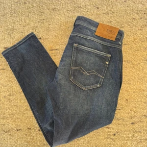 Replay jeans i mörkblå denim, W33 L30 - Snygga mörkblå jeans från Replay med klassisk kontrastsömmar på bakfickorna. Jeansen har en rak passform och är tillverkade i slitstark denim. Perfekta för dig som gillar en stilren och tidlös look. Dom är nästan helt nya bara använda 2-3 gången.