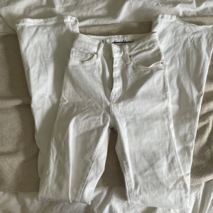 Vita jeansbyxor från Never Denim XS - Snygga vita jeansbyxor från Never Denim i storlek XS. Klassisk femficksmodell med silverfärgad knapp och dragkedja framtill. Byxorna har rak passform och är tillverkade i mjukt bomullstyg som sitter skönt hela dagen.