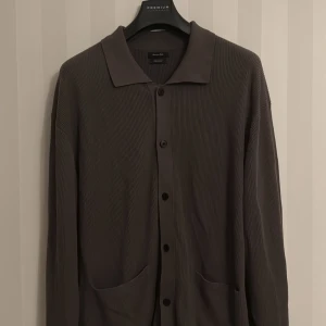 Khakigrön kofta  från Massimo Dutti - Säljer en stilren Khakigrön kofta från Massimo Dutti i 100% bomull. Koftan har ribbad struktur, klassisk krage, knäppning framtill och två fickor. Knappt använd