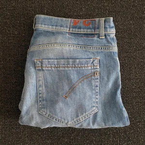 Dondup George Jeans - Ljusblå skinny fit jeans från dondup med klassisk femficksdesign och snygga kontrastsömmar. Jeansen har en enkel bakficka och en diskret dondup-detalj på linningen. Perfekta för dig som gillar en smalare passform och stilren look.