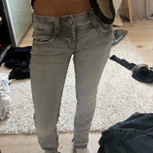 Grå Pepe Jeans Power Flex jeans - Snygga grå jeans från Pepe Jeans Power Flex med raka ben och låg midja. Jeansen har klassiska fem fickor, dubbla knappar i midjan och diskreta sömdetaljer på bakfickorna. Stretchigt material för extra komfort och en clean look.